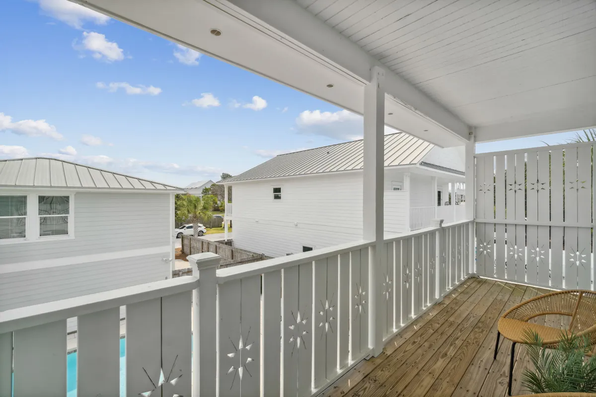 This tranquil exterior shot of a wooden deck with decorative railing and outdoor seating offers a peaceful retreat for socializing, relaxing, or watching the sunset. It suggests a welcoming environment for both families and pets to enjoy the outdoors together.