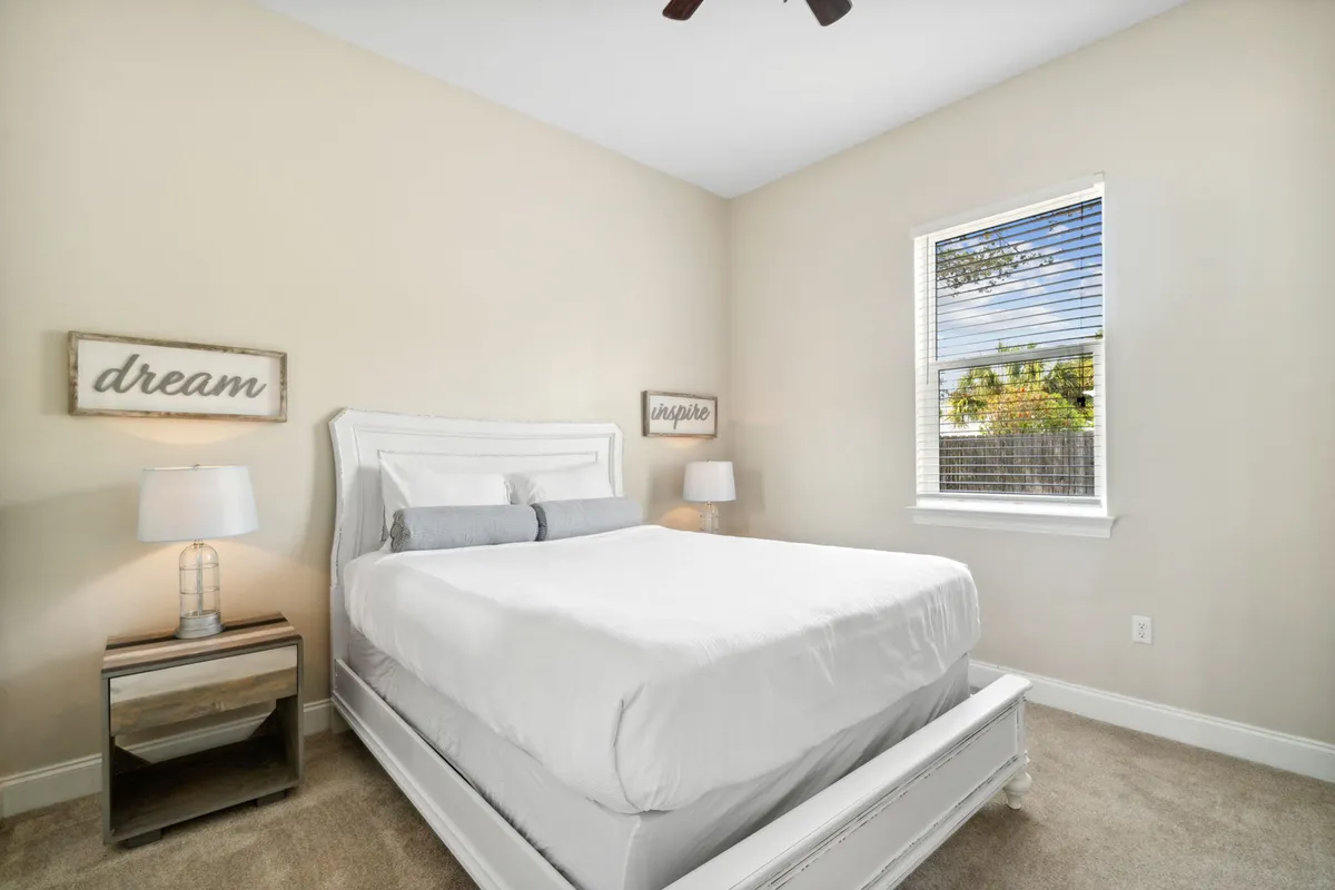 A serene bedroom setting with a neatly made bed, soft white bedding, bedside lamps, and tasteful wall decor. The room feels bright and peaceful, ideal for both restful sleep and gentle morning routines.