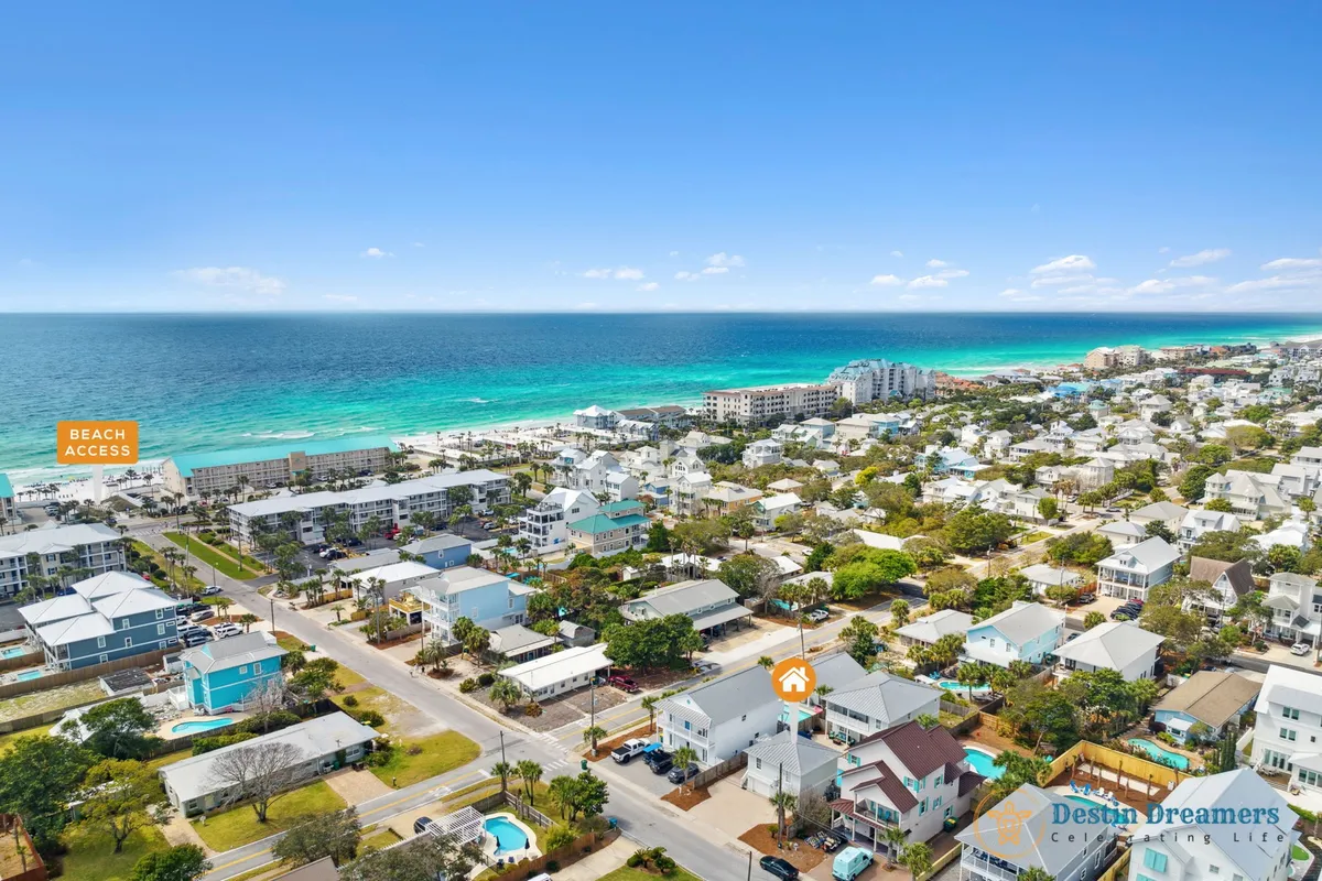 This image features a stunning aerial view of the Destined for Heaven property, showcasing the turquoise ocean, direct beach access, a private pool, and a cluster of charming beach houses. The shot captures the sense of luxurious coastal living and adventure, with the inviting water hinting at VIP activities like parasailing, dolphin cruises, and sunset strolls.