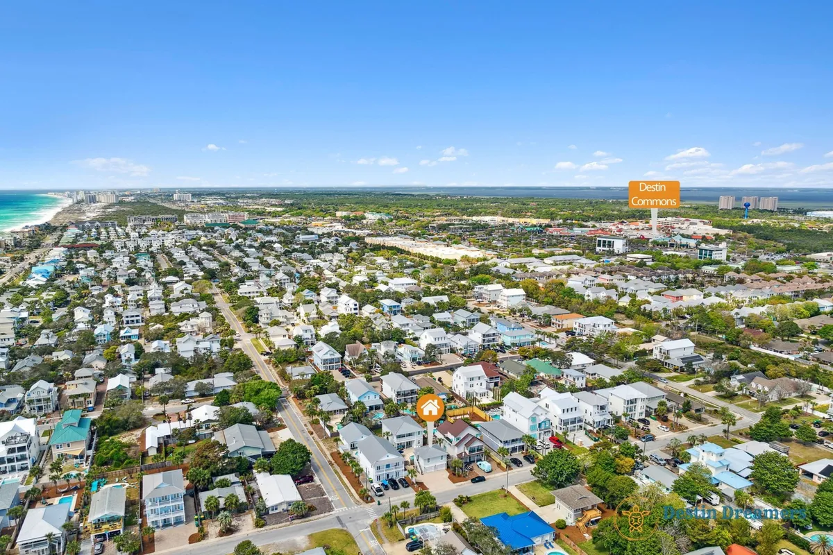 A bird’s-eye view of the Destined for Heaven property set among coastal-style homes, with the location marked for clarity. The image captures neighboring houses, the distant beach and ocean, and Destin Commons shopping area in the background, emphasizing the property's prime location and easy access to local attractions.